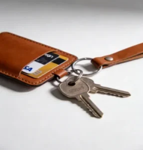 A leather keychain wallet holding credit cards, attached to a metal key ring with house keys on a clean surface